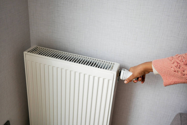 les femmes ajustent à la main la température d'un radiateur. - Photo, image