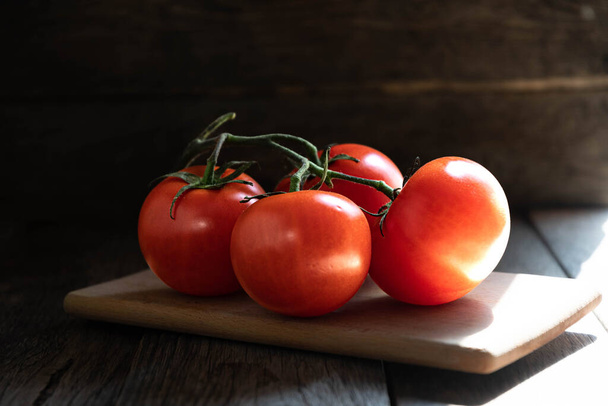 Une branche de tomates mûres sur une planche à découper dans la cuisine. - Photo, image