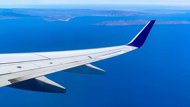 Samoloty przelatujące nad Oceanem Spokojnym i zbliżające się do lotniska w meksykańskim stanie Baja California, w krajobrazie łąkającym piękne błękitne niebo z morzem. Koncepcja statku powietrznego. - Zdjęcie, obraz