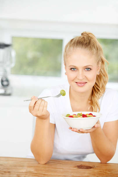 Fruit salad, eating or portrait of happy woman with a snack, morning breakfast or lunch diet in home kitchen. Face, gut health or girl with fruits, grapes or food bowl meal to lose weight or wellness. - Foto, afbeelding