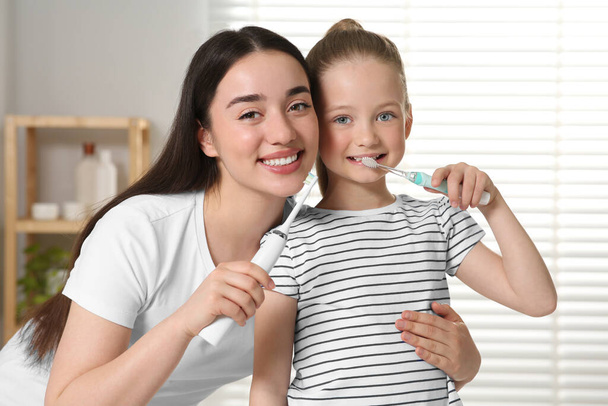 Mother and her daughter brushing teeth together in bathroom - Zdjęcie, obraz