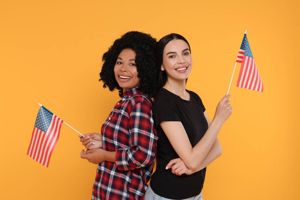 4 luglio - Giorno di indipendenza degli Stati Uniti. Donne felici con bandiere americane su sfondo giallo - Foto, immagini
