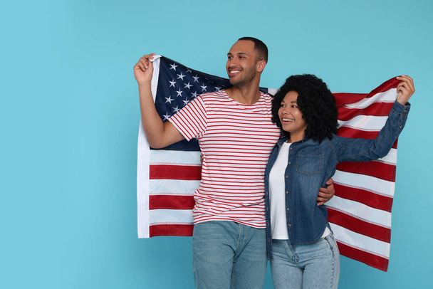 4th of July - Independence Day of USA. Happy couple with American flag on light blue background - 写真・画像