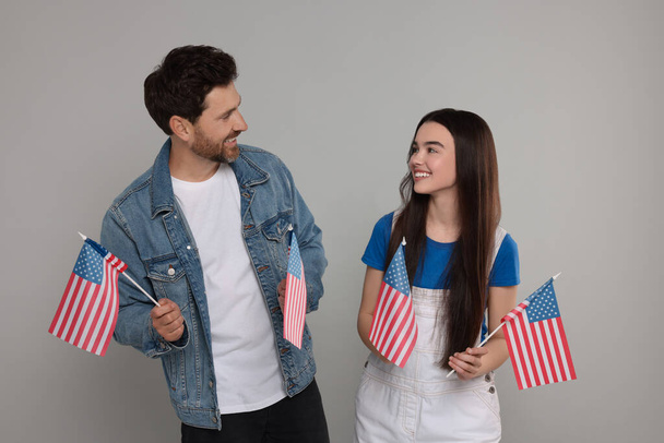 4th of July - Independence Day of USA. Happy father and his daughter with American flags on light grey background - Foto, imagen