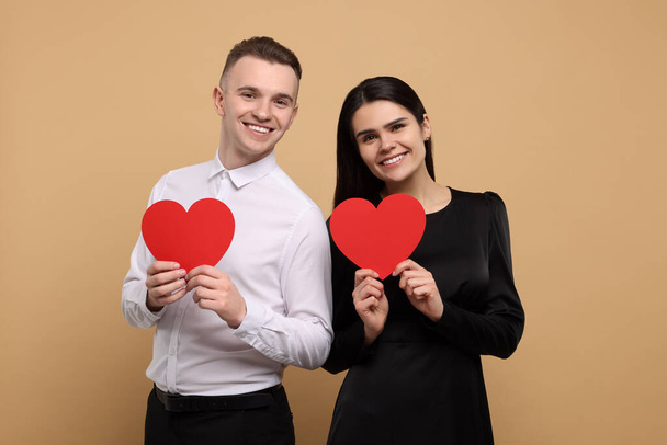 Lovely couple with decorative hearts on beige background. Valentine's day celebration - Foto, Bild