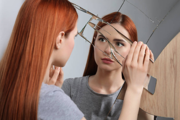 Sad young woman suffering from mental problems near broken mirror - Foto, Imagem