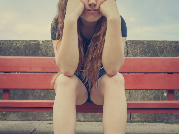 Sad funny teenage woman being worried. Frustrated female waiting for somebody while sitting on bench outdoor. - Foto, imagen