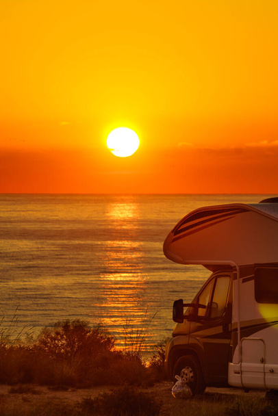 Sun rising over sea horizon, day break and caravan parking on beach sea shore. Travel with mobile home. - Foto, afbeelding