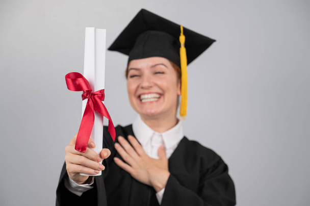 Smiling woman in graduation gown holding diploma on white background - Valokuva, kuva