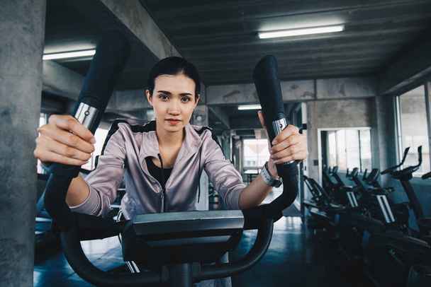 Sportowa azjatycka kobieta ćwiczy na eliptycznej maszynie w siłowni, ćwiczenia cardio - Zdjęcie, obraz