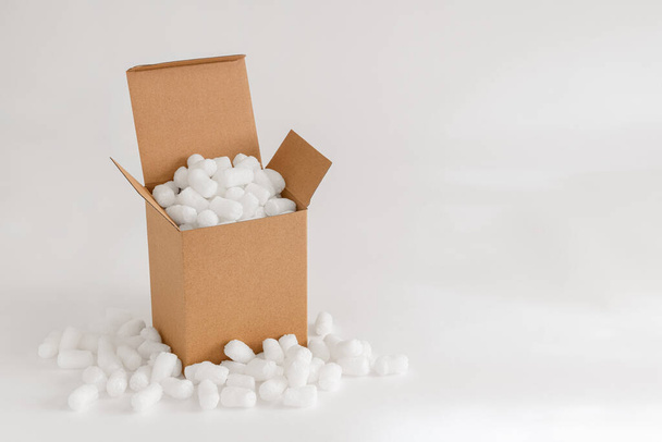 Cardboard box isolated on the white background filled with packing peanuts - Photo, Image