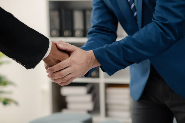Two businessmen holding hands, Two businessmen are agreeing on business together and shaking hands after a successful negotiation. Handshaking is a Western greeting or congratulation. - Photo, Image