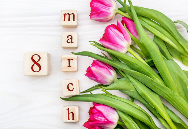 Wooden cubes with date of 8 march and tulips on the wooden background. Holiday background. Top view. - Foto, Imagem