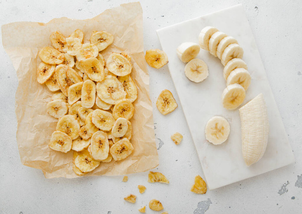 Fresh banana and baked crunchy chips snack on light background. - Photo, Image