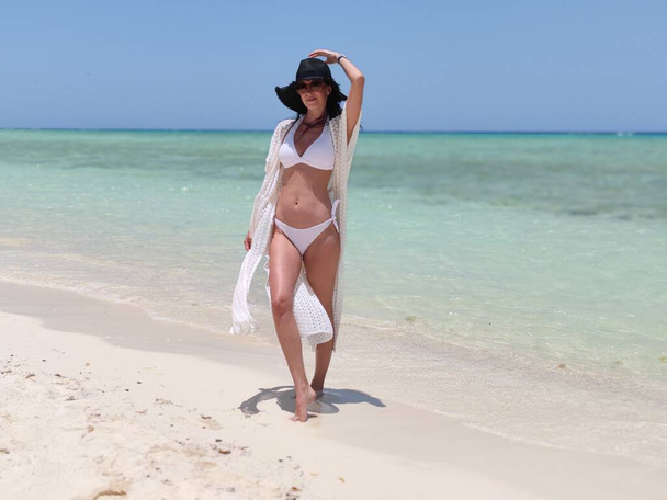Slim brunette girl, woman on the beach in bikini with sunglasses - Valokuva, kuva