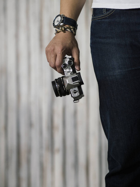 Man in white shirt and blue jeans with Right hand holding camera wearing seiko blue and white watch and bracelet - Photo, Image