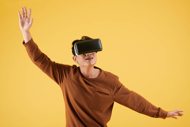 Excited young man playing video game in virtual reality glasses - Fotó, kép