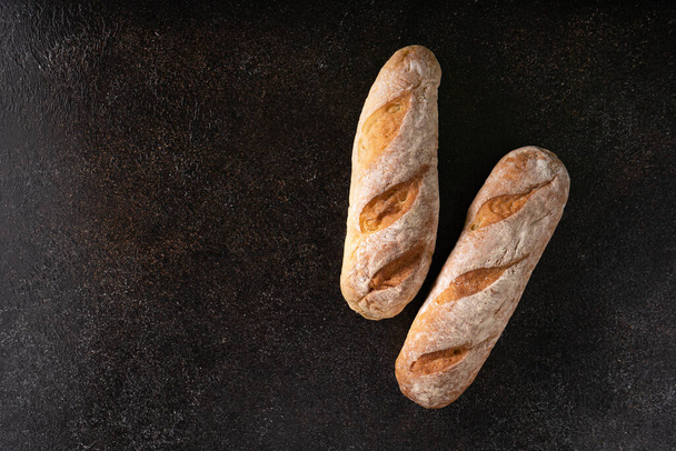 Fresh homemade artisan loaf of baguette breads on rustic background with copy space. sourdough mini baguette breads. - Photo, image
