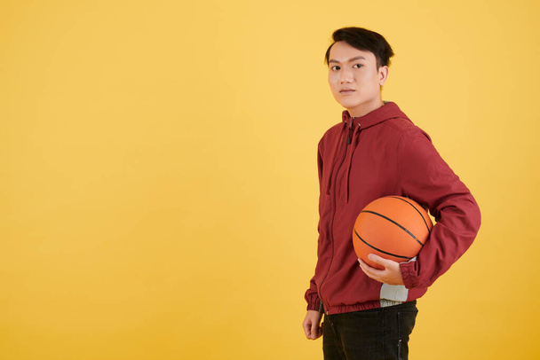 Estudio retrato de joven asiático sosteniendo pelota de baloncesto - Foto, imagen