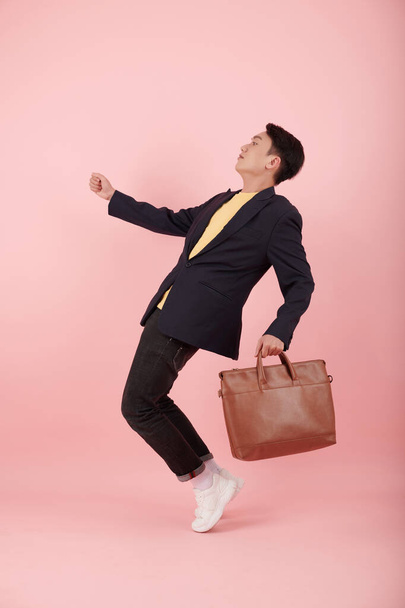 Studio portrait of young Asian entrepreneur with faux leather bag doing toe stand - Foto, Imagem