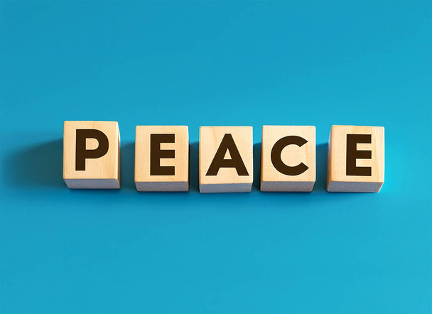 Peace displayed on wooden letter blocks on pastel blue background. - Photo, image