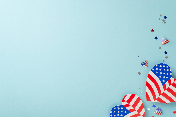 Wir feiern den 4. Juli. Blick von oben auf repräsentative Verzierungen: Herzen mit amerikanischem Flaggenmuster, glitzerndes Konfetti, arrangiert auf pastellblauem Hintergrund mit Platz für Werbung - Foto, Bild