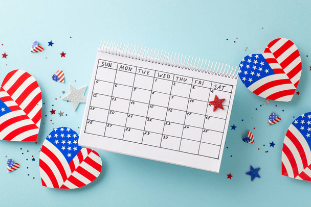 Celebrating Independence Day: Top view of symbolic decor, calendar with date emphasized, hearts showcasing American flag pattern, confetti scattered about. Soft blue backdrop with space for note - Photo, Image