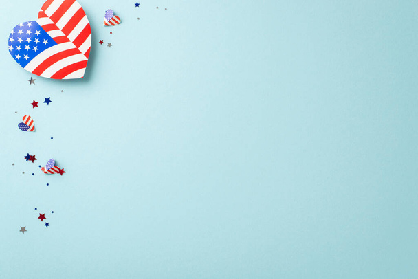 Happy Independence Day USA! Overhead perspective of festive ornaments: heart featuring US flag design, confetti in thematic colors on pastel blue backdrop with empty space for text or promo content - Photo, image