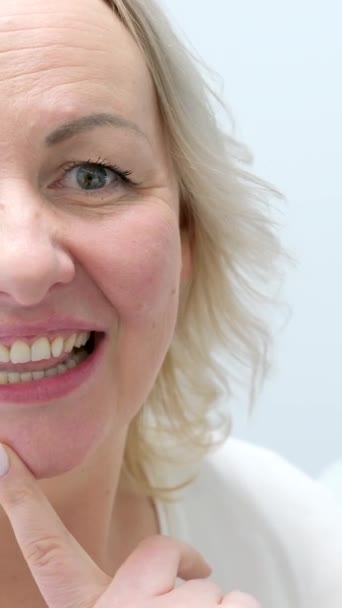 hermosa joven mujer de mediana edad admirándose en el espejo en la silla dental después de procedimiento de blanqueamiento limpieza de dientes relleno guiños complacidos en el marco  - Metraje, vídeo