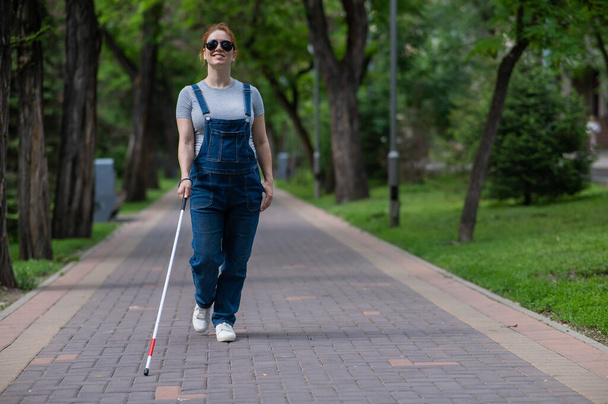 Blind pregnant woman walking in the park with a cane - Foto, immagini