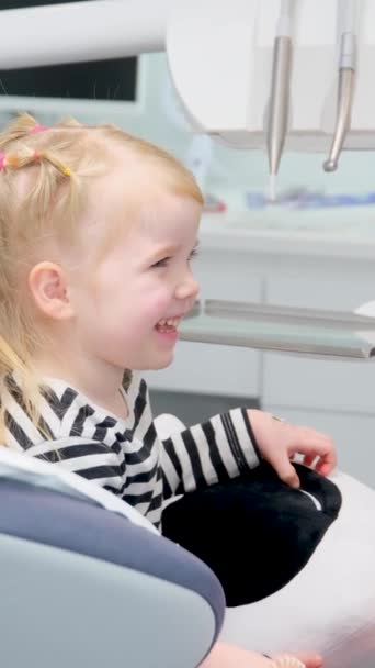 radość w fotelu u dentysty dziewczyna spotyka lekarza uśmiecha się nieśmiały patrzy w oczy lekarz prostuje bluzkę włosy i mówi o narzędziach strach  - Materiał filmowy, wideo