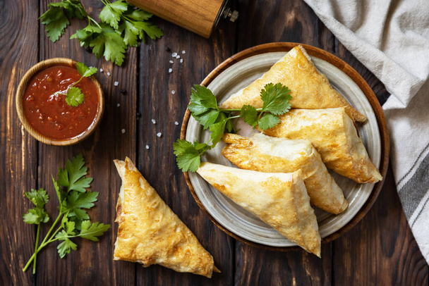 Asian food. Vegetarian samsa (samosas) with tomato sauce on a wooden table. Popular in Indonesia as Risoles Sayur. View from above. - Fotografie, Obrázek