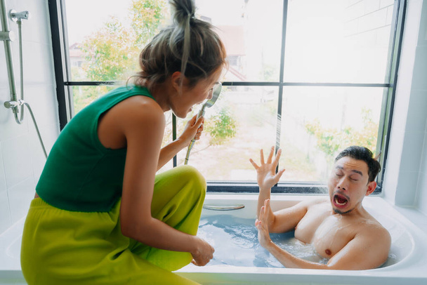 Funny playful asian couple lover play in a bathtub in the bathroom. - Фото, изображение