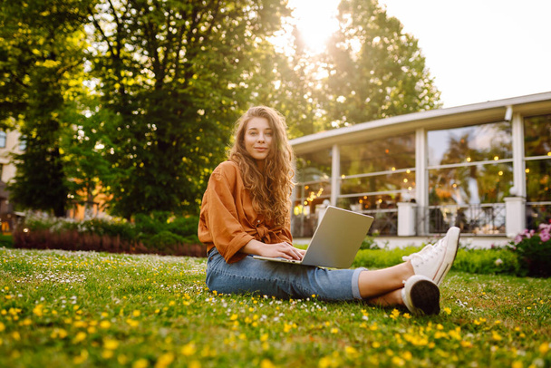 Smiling young woman with a laptop working or studying online outdoor. Concept for education, business, blog or freelance. - Foto, Imagen
