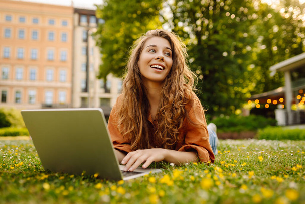 Smiling young woman with a laptop working or studying online outdoor. Concept for education, business, blog or freelance. - Foto, Imagem