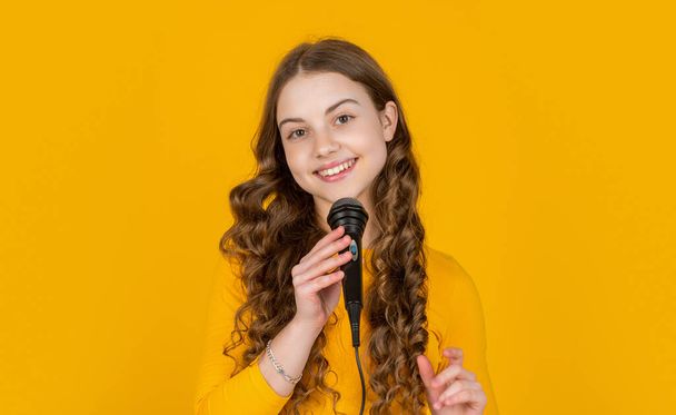 glad teen girl with microphone on yellow background. - Fotografie, Obrázek