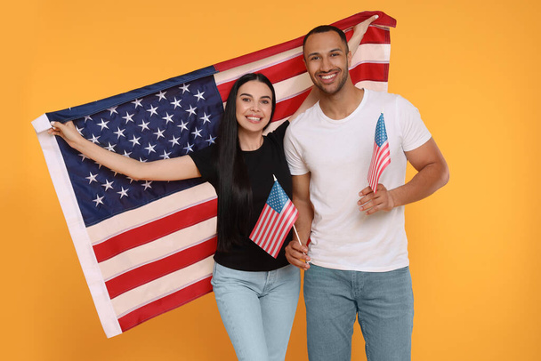 4th of July - Independence Day of USA. Happy couple with American flags on yellow background - Photo, Image