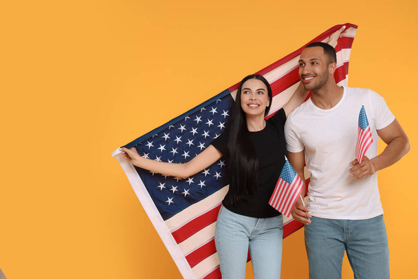 4th of July - Independence Day of USA. Happy couple with American flags on yellow background, space for text - Фото, зображення