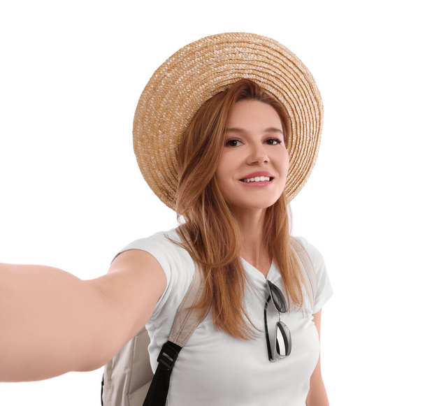 Beautiful woman in straw hat taking selfie on white background - 写真・画像