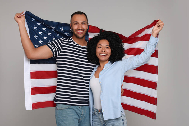 4th of July - Independence Day of USA. Happy couple with American flag on grey background - Photo, image