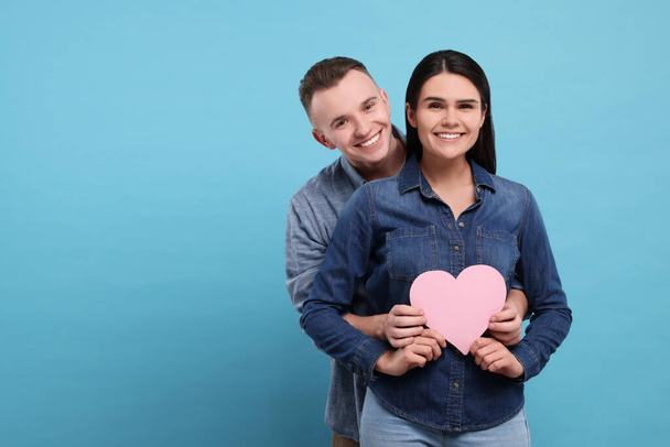 Lovely couple with decorative heart on light blue background, space for text. Valentine's day celebration - Foto, immagini