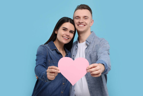 Lovely couple with decorative heart on light blue background. Valentine's day celebration - Fotografie, Obrázek