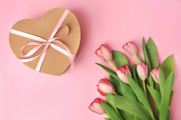 Heart shaped gift box with bow and beautiful tulips on pale pink background, flat lay - Fotoğraf, Görsel