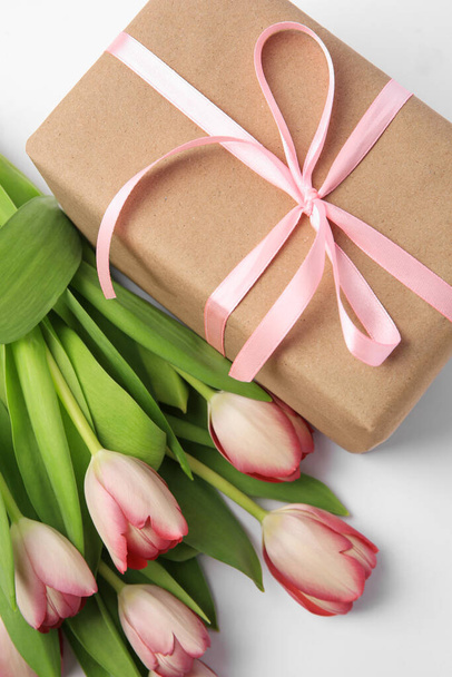 Beautiful gift box with bow and pink tulips on white background, flat lay - Φωτογραφία, εικόνα