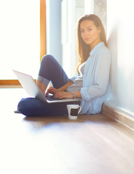 Young beautiful woman at home sitting on the floor with laptop. Young beautiful woman - Фото, изображение