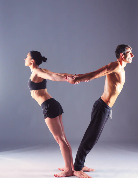 Young couple practicing acro yoga on mat in studio together. Acroyoga. Couple yoga. Partner yoga - Foto, imagen
