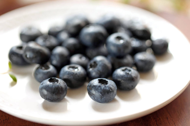 Fresh blueberries served on a white plate - Fotó, kép