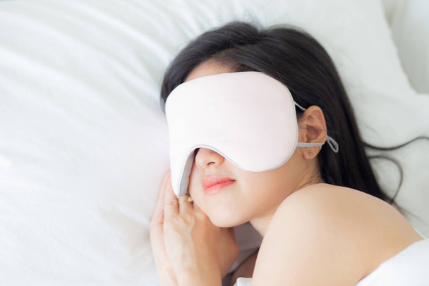 Красивая молодая азиатская женщина с прикрытием глаз и спать на кровати с головой на подушку комфорта и счастья в спальне дома, девушка с отдыхом и отдыха для оздоровления, стиль жизни концепции. - Фото, изображение