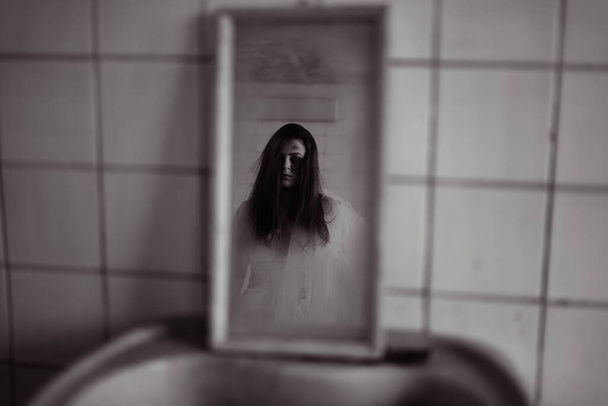 Aynada ürkünç bir yüzle korku filmi sahnesi, beyaz elbiseli ölü gelin yansıması. Cadılar Bayramı sahne konsepti - Fotoğraf, Görsel