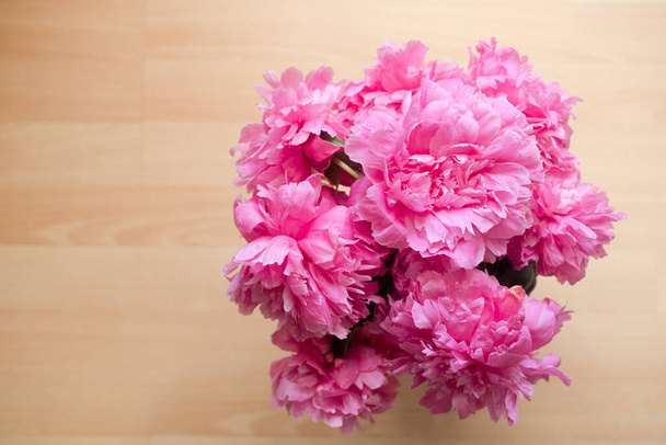 The peony or paeony pink flowers in the vase top view. Paeonia "Sarah Bernhardt" bouquet on wooden background - Photo, Image